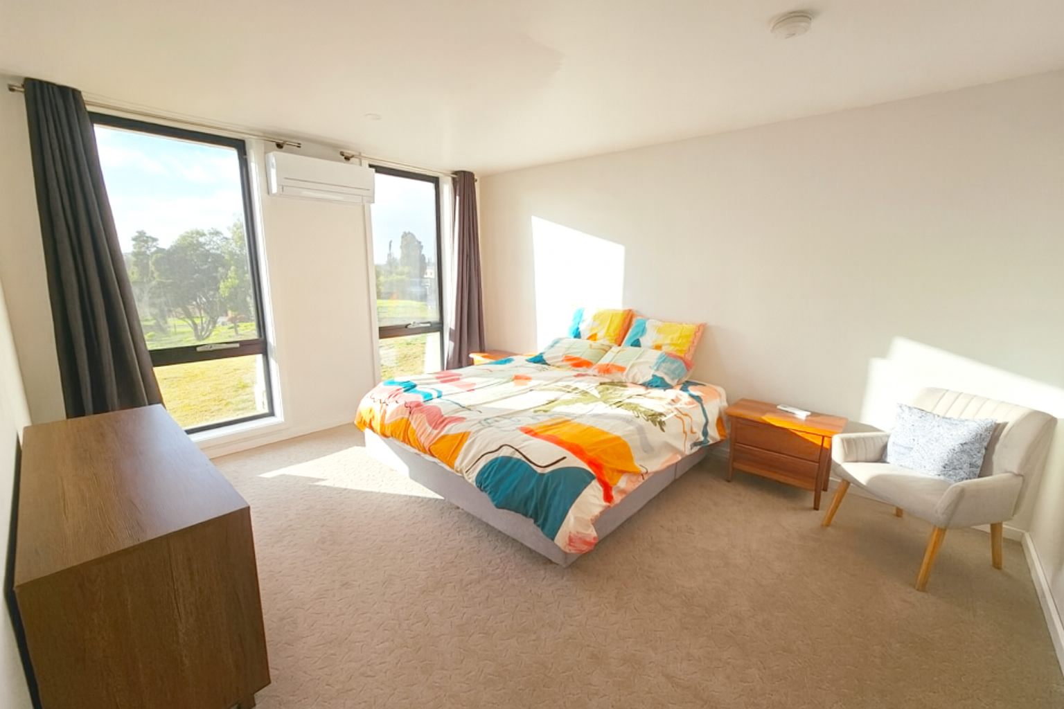 Bright, modern bedroom at Discovery Views Nelson with large windows, natural light, and countryside views.